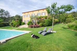 Ein Poolbereich mit Hund, Pool und Gebäude mit einem gefliesen Dach und Rollläden.