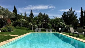A rectangular swimming pool with clear blue water, surrounded by a well-maintained lawn and various trees. - Comfort double beige room (Cabriès)