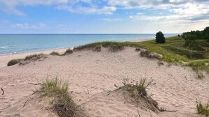 A beach with a sandy shore and grassy dunes.