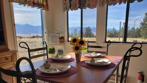 Une table à manger dressée avec des assiettes, des couverts et un vase rempli de tournesols.