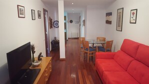 A living room with a red sofa, a TV, and a dining area with chairs and a table. - Vicus Apartments, with excellent views of the Plaza Mayor de Vic (Vic)