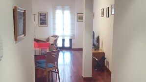 A hallway with wooden flooring, a dining area with chairs and a table, and a living room with a sofa and a TV. - Vicus Apartments, with excellent views of the Plaza Mayor de Vic (Vic)