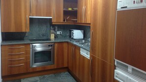 A kitchen with wooden cabinets, a stainless steel oven, a microwave, and a built-in dishwasher. - Vicus Apartments, with excellent views of the Plaza Mayor de Vic (Vic)