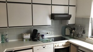 Una cocina compacta con armarios blancos, lavavajillas, horno y pileta.