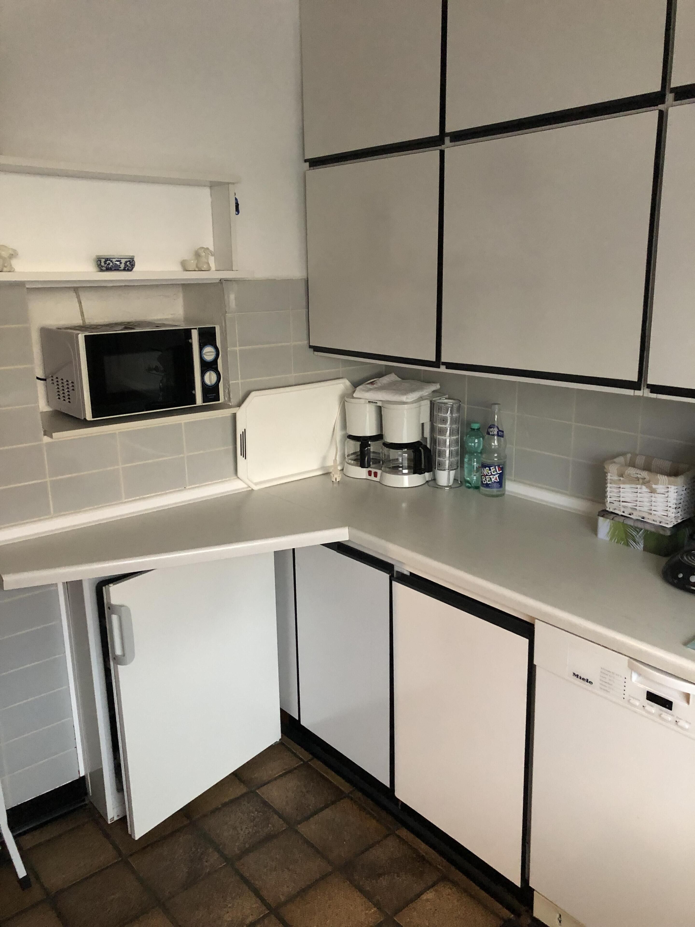 A compact kitchen with a microwave, coffee maker, and a dishwasher.