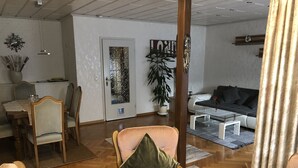 Una sala de estar con comedor, un sofá, una mesa de centro y una puerta con paneles de vidrio decorativos.
