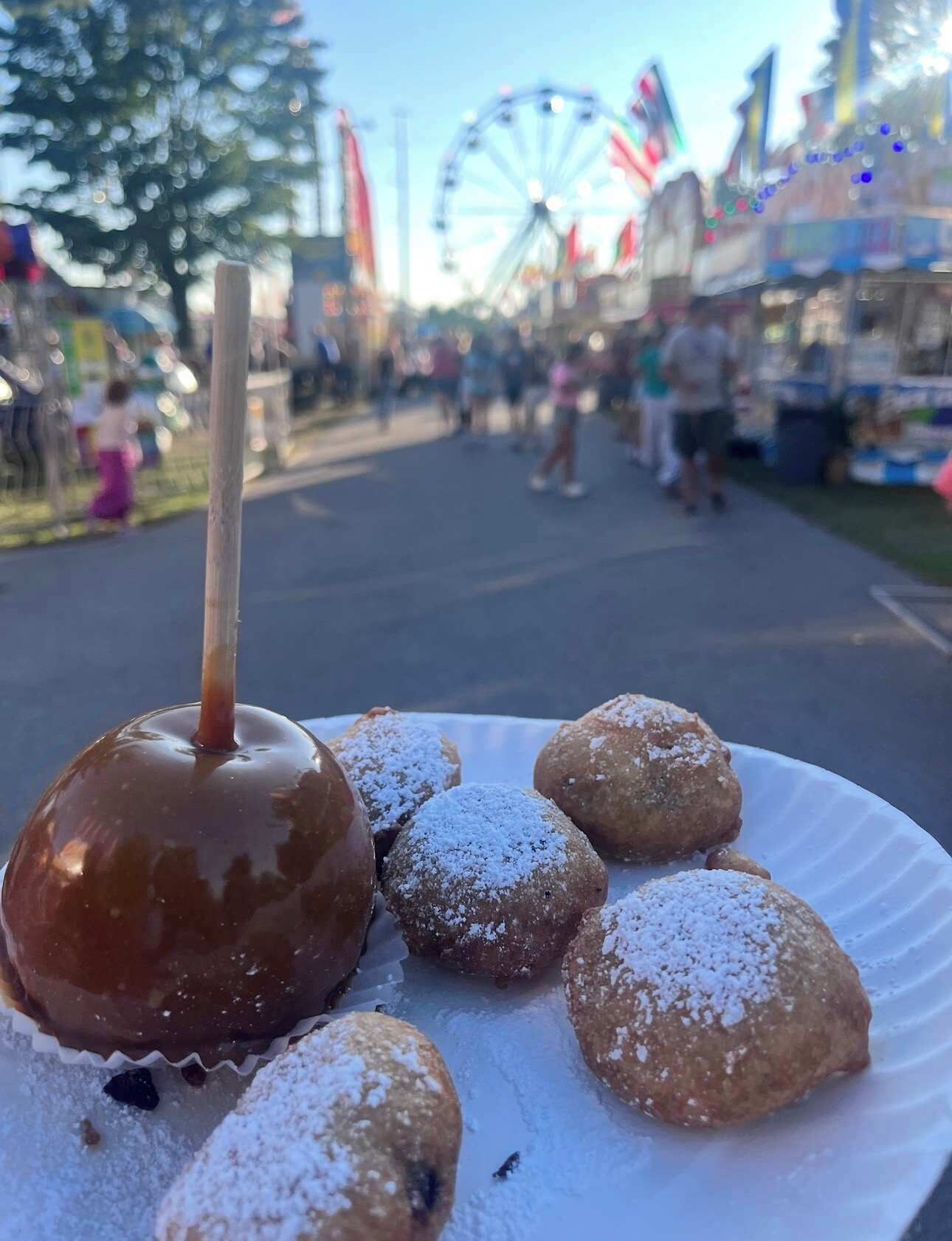 Een bord met een appel in karamel en gesuikerde donuts.