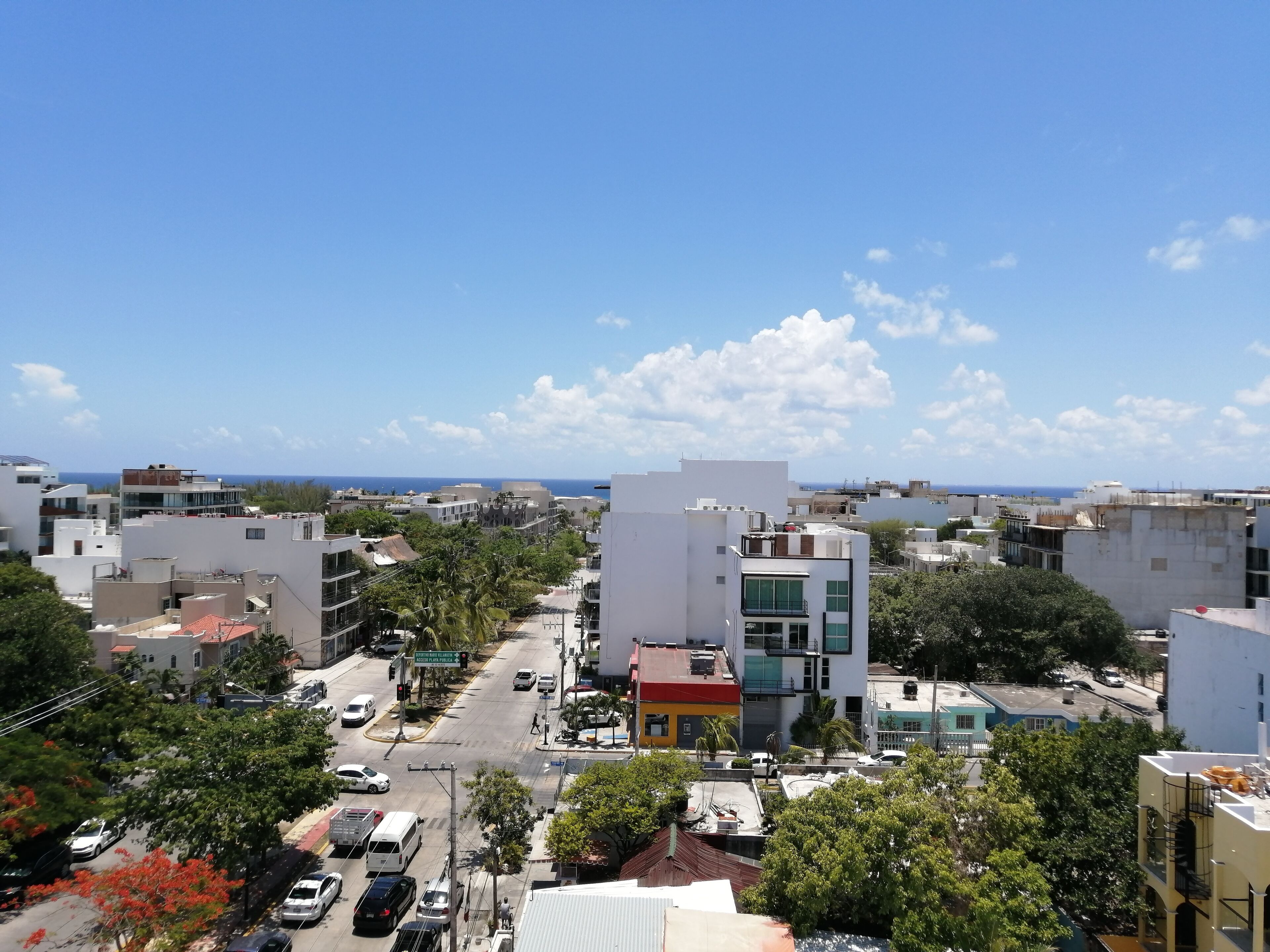 A cityscape with modern buildings, a clear sky, and a view of the sea.