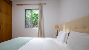 Una camera da letto con un letto, una finestra con tende, una lampada da comodino e un armadio in legno.