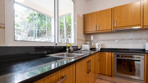Una cucina con mobili in legno, un lavello in acciaio inossidabile e un forno a incasso.