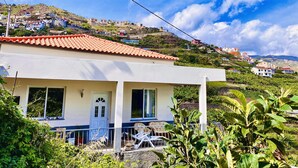 Una casa a un piano con tetto in tegole rosse, facciata bianca e un piccolo portico con ringhiera.