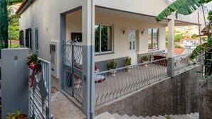 Una casa a due piani con un balcone, un piccolo giardino e una porta ben visibile.