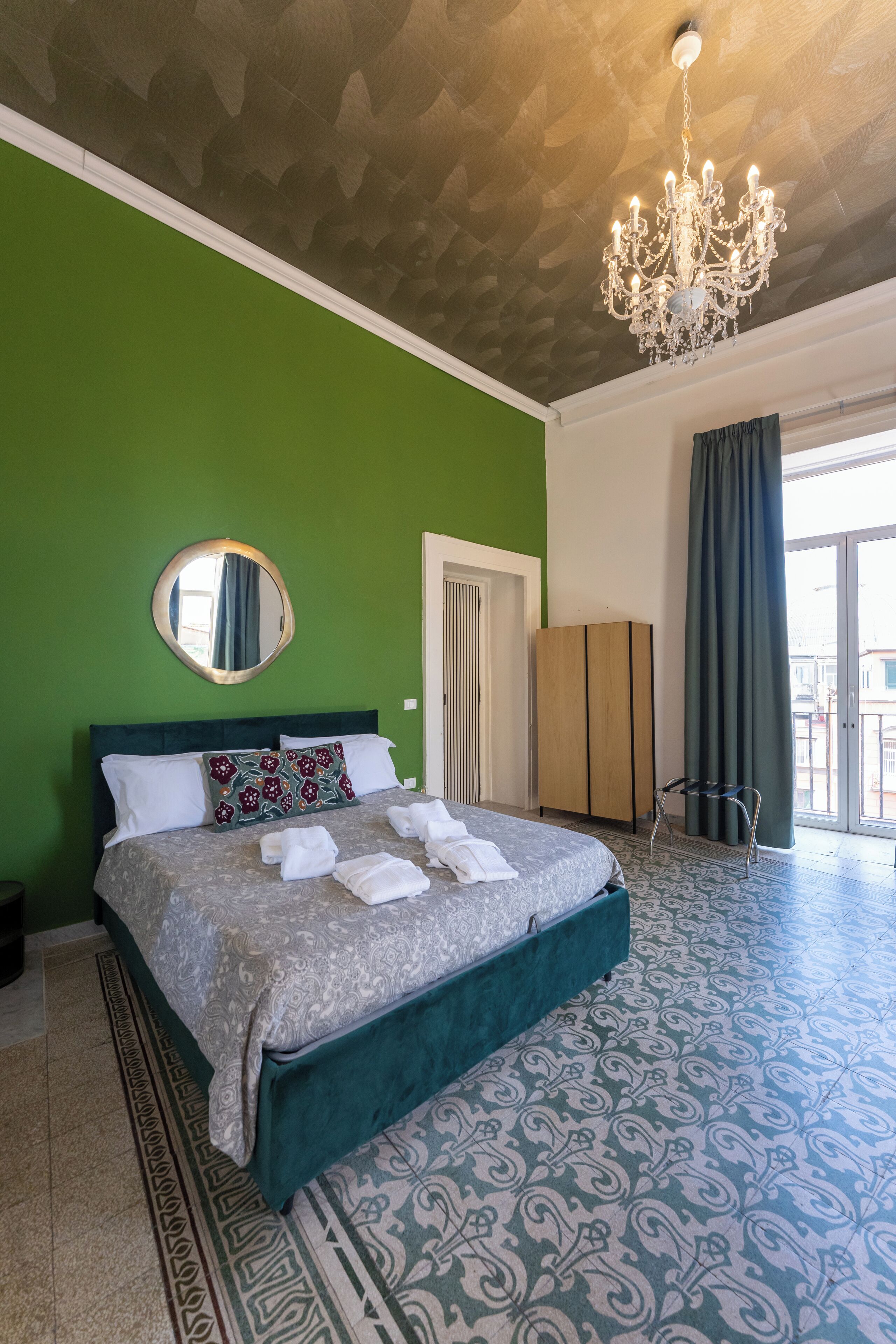 Une chambre à coucher avec un grand lit, un lustre, un miroir et une vue sur l’extérieur grâce à une porte coulissante.