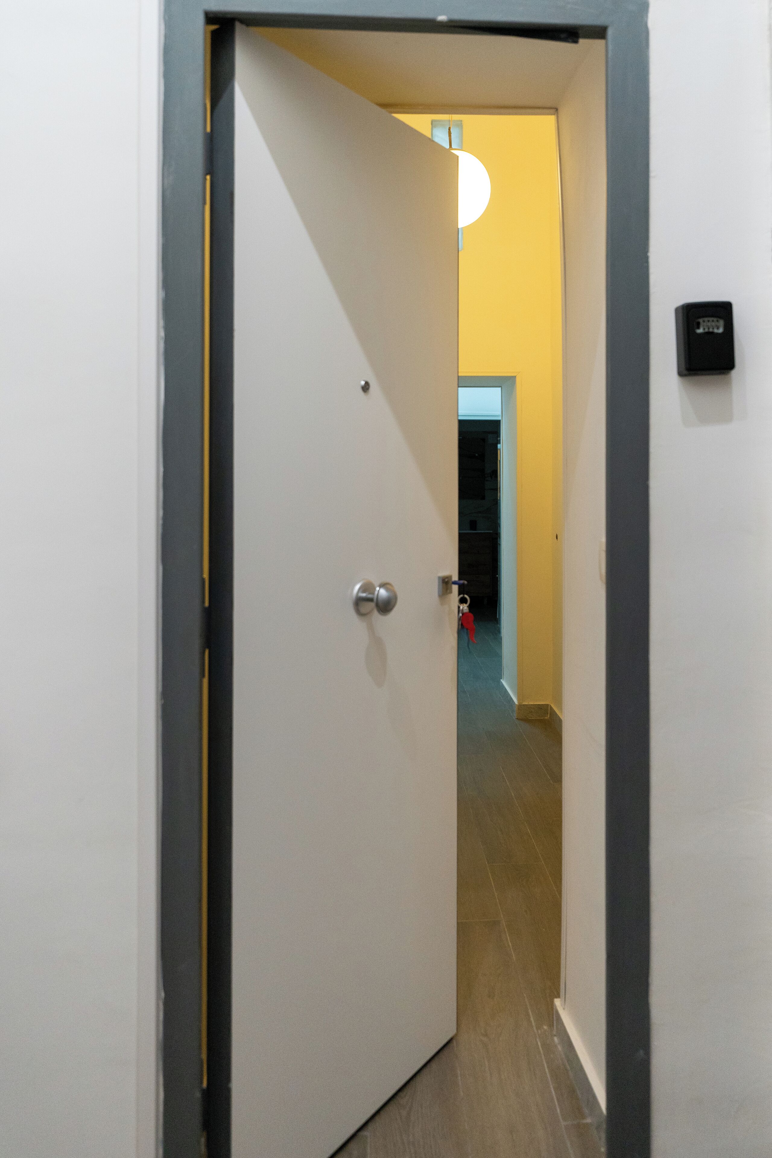 A hallway with a white door, a light fixture, and a doorbell.