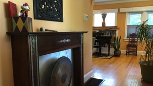 Uma sala de estar com lareira, piano e planta em vaso.