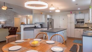 A modern kitchen with white cabinets, a central island, and a dining area with a wooden table and chairs.