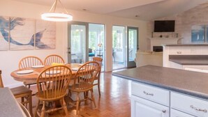 A modern kitchen with wooden chairs, a dining table, and a large island with a granite countertop.