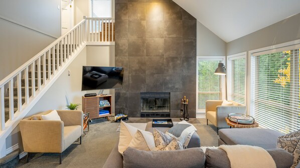 Ein modernes Wohnzimmer mit Kamin, Fernseher und Treppe.