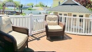 Eine überdachte Terrasse mit Korbmöbeln und einem weißen Geländer.