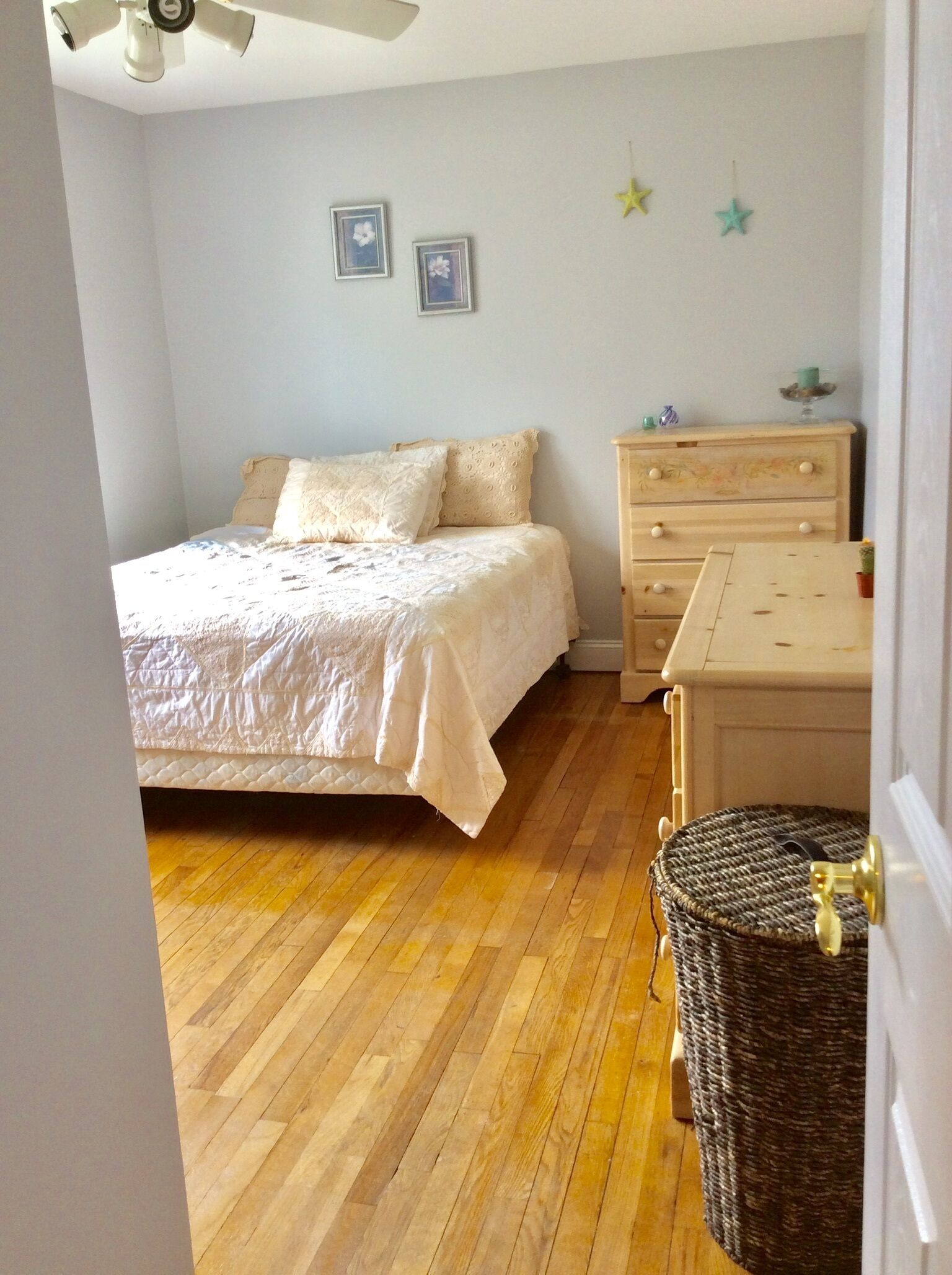 Ein Schlafzimmer mit Bett, Kommode und Deckenventilator.