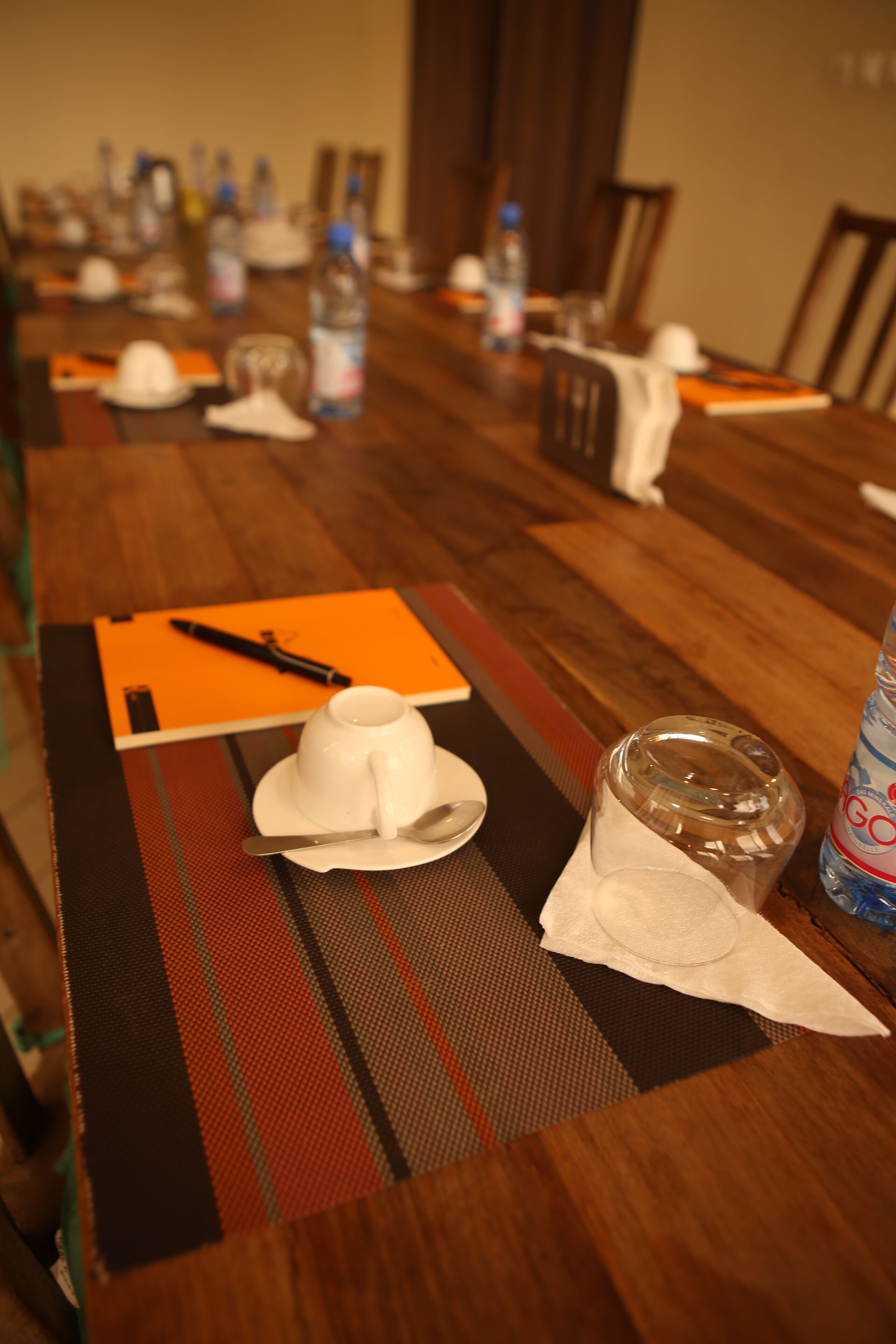 A dining table set with a white hat, a glass, and a bottle of water.