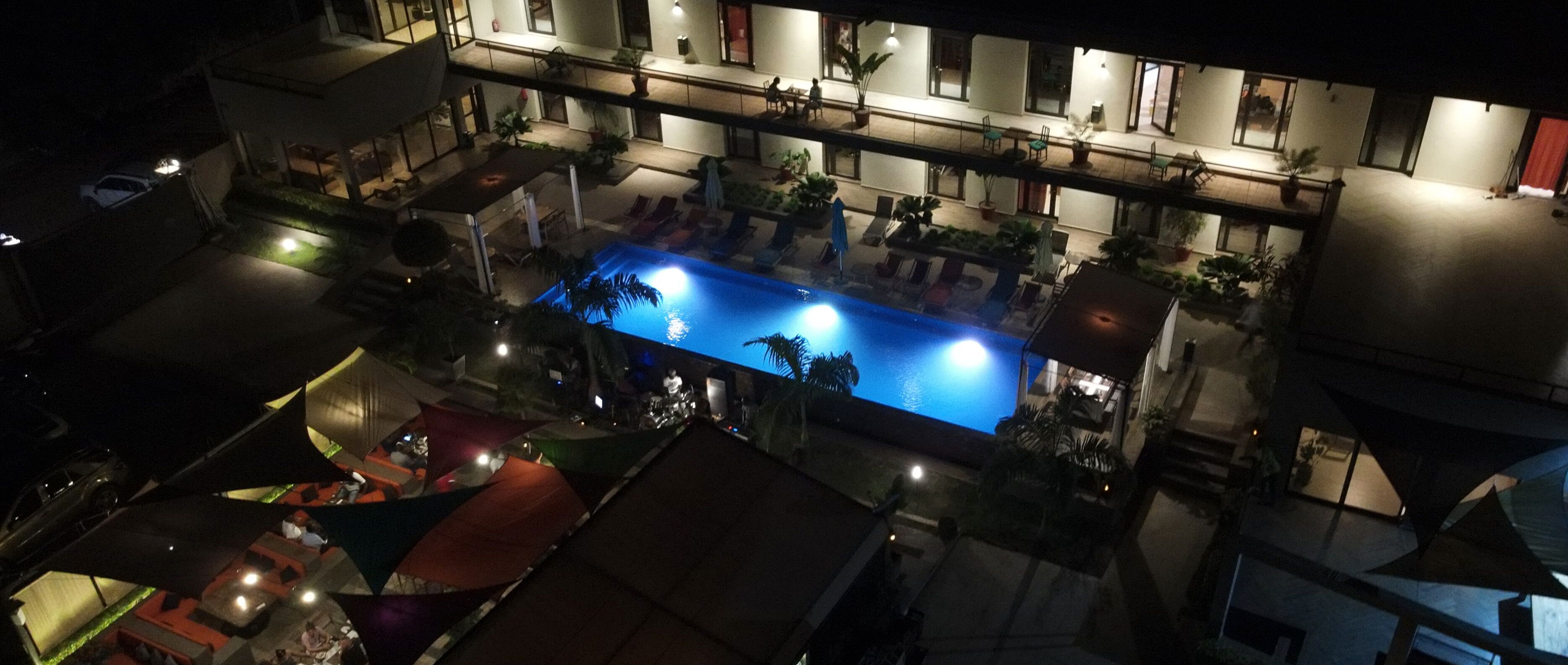 An aerial view of a hotel with a swimming pool, outdoor seating, and multiple balconies.