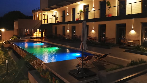 Un edificio moderno con piscina, asientos exteriores y una entrada bien iluminada.