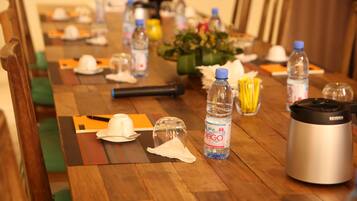 Una mesa de conferencias con botellas de agua, una cafetera y un arreglo floral.
