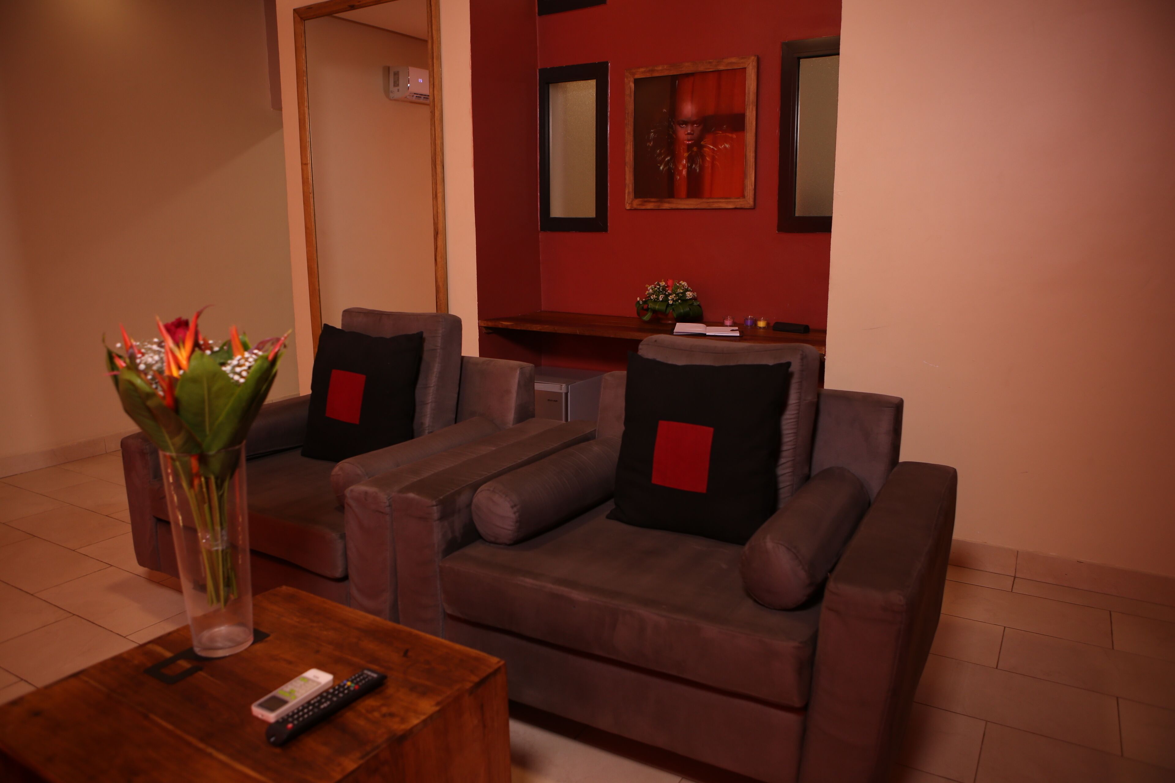 A living room with a brown sofa, a wooden coffee table, and a vase with flowers.