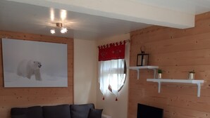 Una sala de estar acogedora con un sofá modular, una mesita de centro, un mueble para televisión y un cuadro de un oso polar.