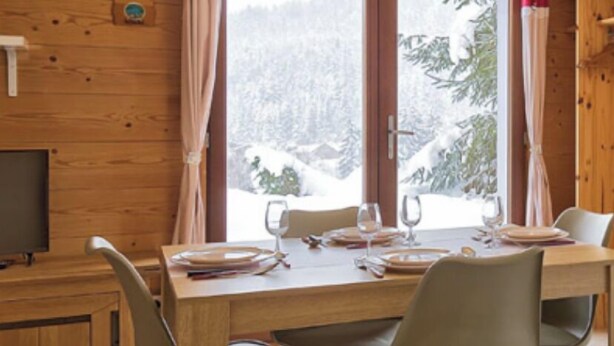 Un interior de madera con una mesa de comedor, sillas y un televisor.