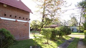 A brick building with a red roof, surrounded by a well-maintained lawn and a small tree.