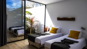 A modern hotel room with two beds, a large sliding glass door to a balcony, and a minimalist decor. - FURNAS HOUSES South (19A) (FURNAS)