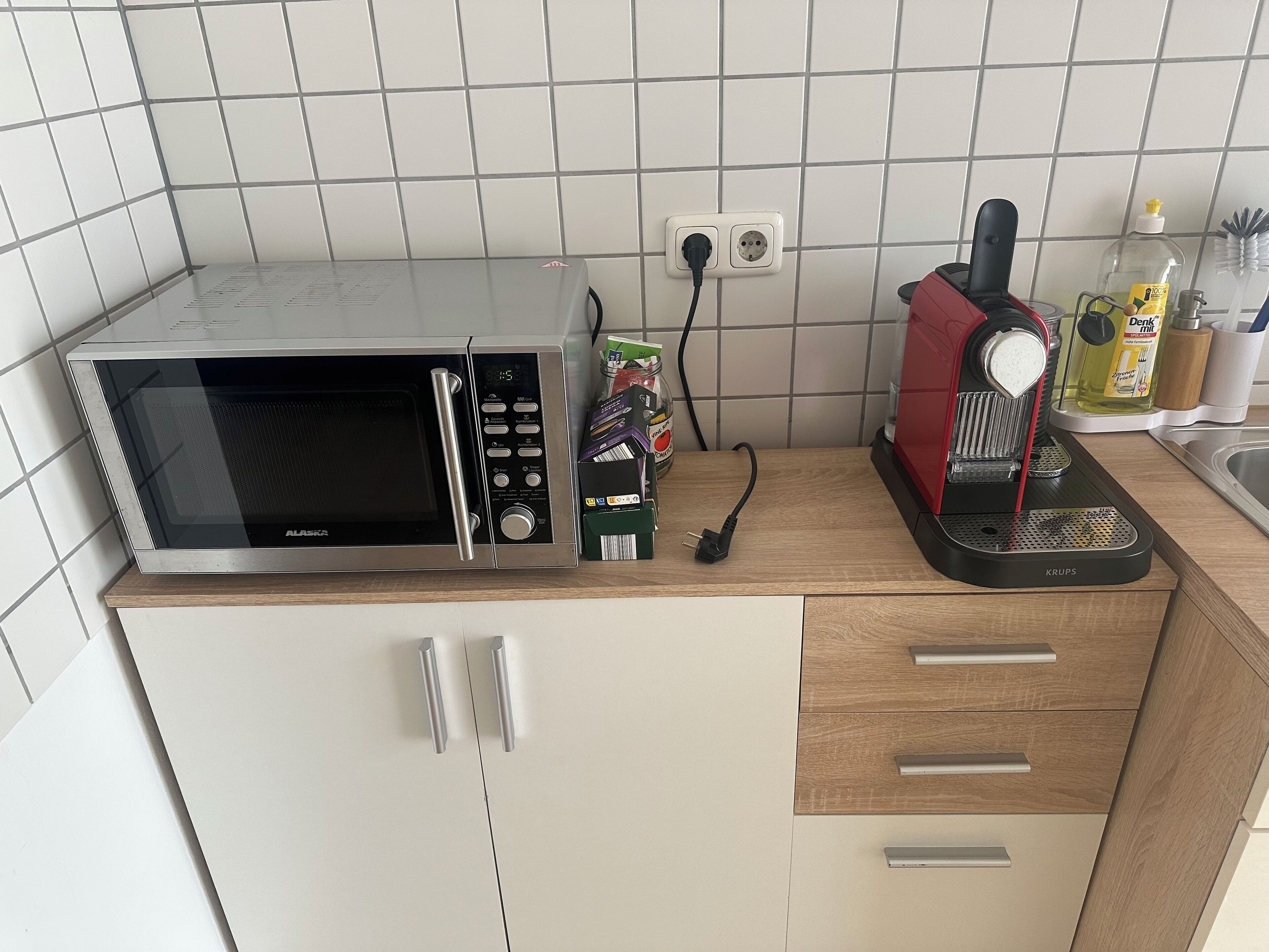 Une cuisine équipée d’un four à micro-ondes, d’une machine à café et d’une prise électrique au mur.