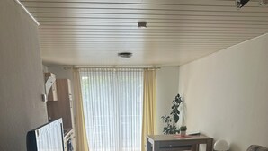 A modern living room with a flat-screen TV, a sofa, a coffee table, and a dining area. - Susi's Apartment - 60m2 for 2 persons, quiet location and handicapped accessible (Waldgirmes)