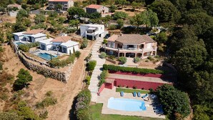 An aerial view of a residential area with multiple houses, a swimming pool, and a red-roofed building.