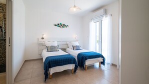 A bedroom with two beds, a shower area, and a large window.
