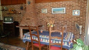 Un coin repas avec un mur en briques, un téléviseur, une cheminée et une table avec des chaises.