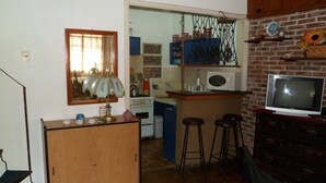 Une cuisine compacte équipée d’un four à micro-ondes, d’un petit coin bar et d’un téléviseur.