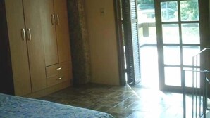 Une chambre à coucher comprenant un lit, une armoire et une porte donnant sur un balcon.