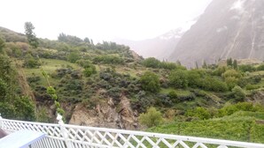A mountainous landscape with lush greenery and rocky cliffs. - Hunza holiday Inn (Karimabad)