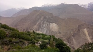 A mountainous landscape with a valley in the foreground and snow-capped peaks in the background. - Hunza holiday Inn (Karimabad)