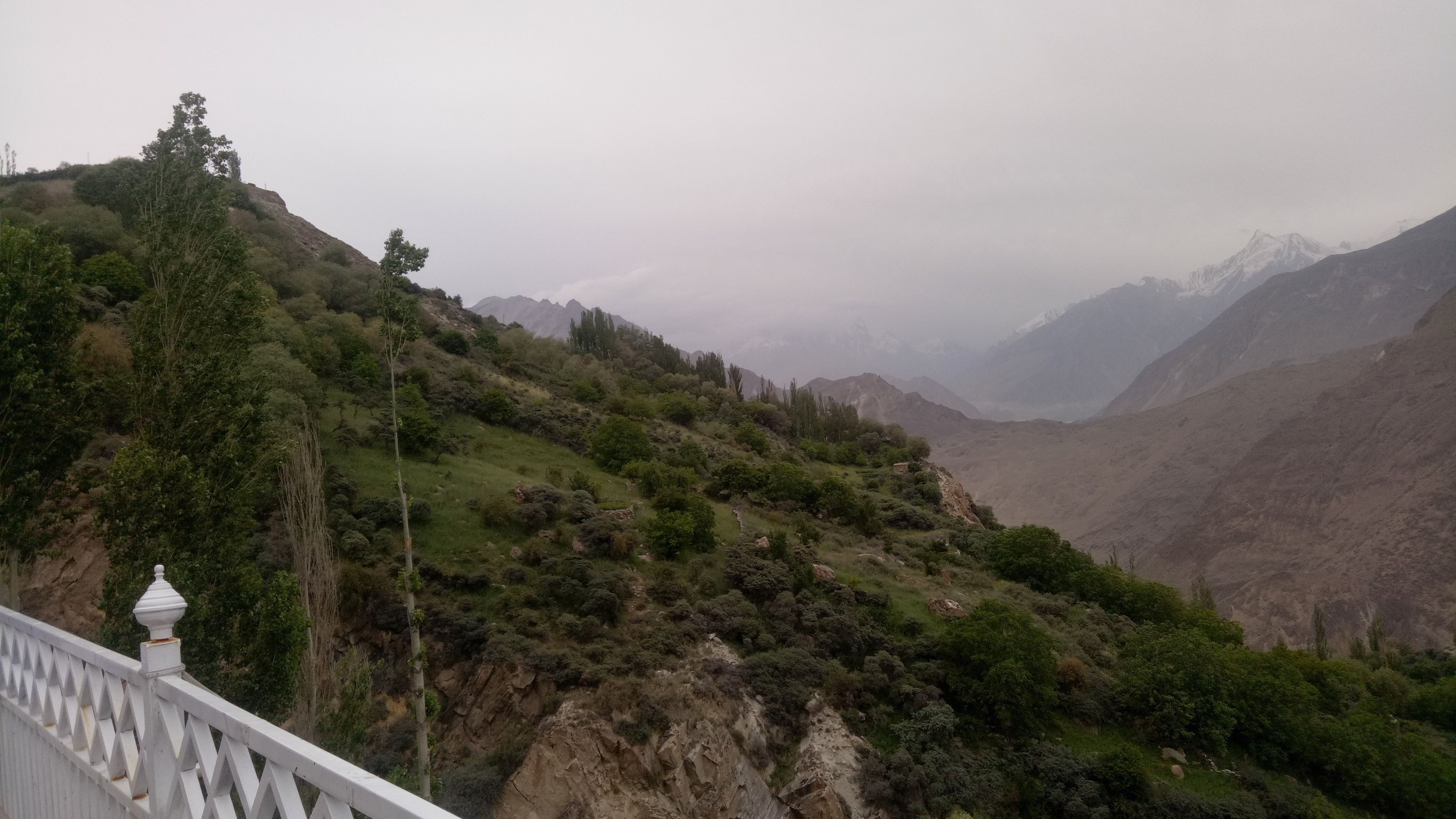 Un paisaje montañoso con una barandilla blanca y una pequeña construcción a la izquierda.