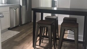 A modern kitchen with stainless steel appliances, a dark wooden table, and two stools. - Perfect, Walking Distance to Downtown Social District, Grand Haven!  (Grand Haven)