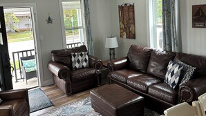 A spacious living room with a brown leather sofa set, a patterned rug, and a dining table. - Perfect, Walking Distance to Downtown Social District, Grand Haven!  (Grand Haven)