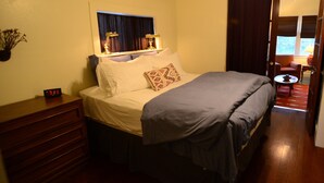 A bedroom with a bed, bedside table, lamp, and a clock.