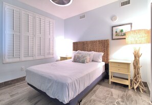 Une chambre à coucher avec un lit, des tables de chevet, une lampe et un tableau au mur.