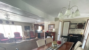 Uma sala de jantar com uma mesa de madeira, cadeiras e um lustre.
