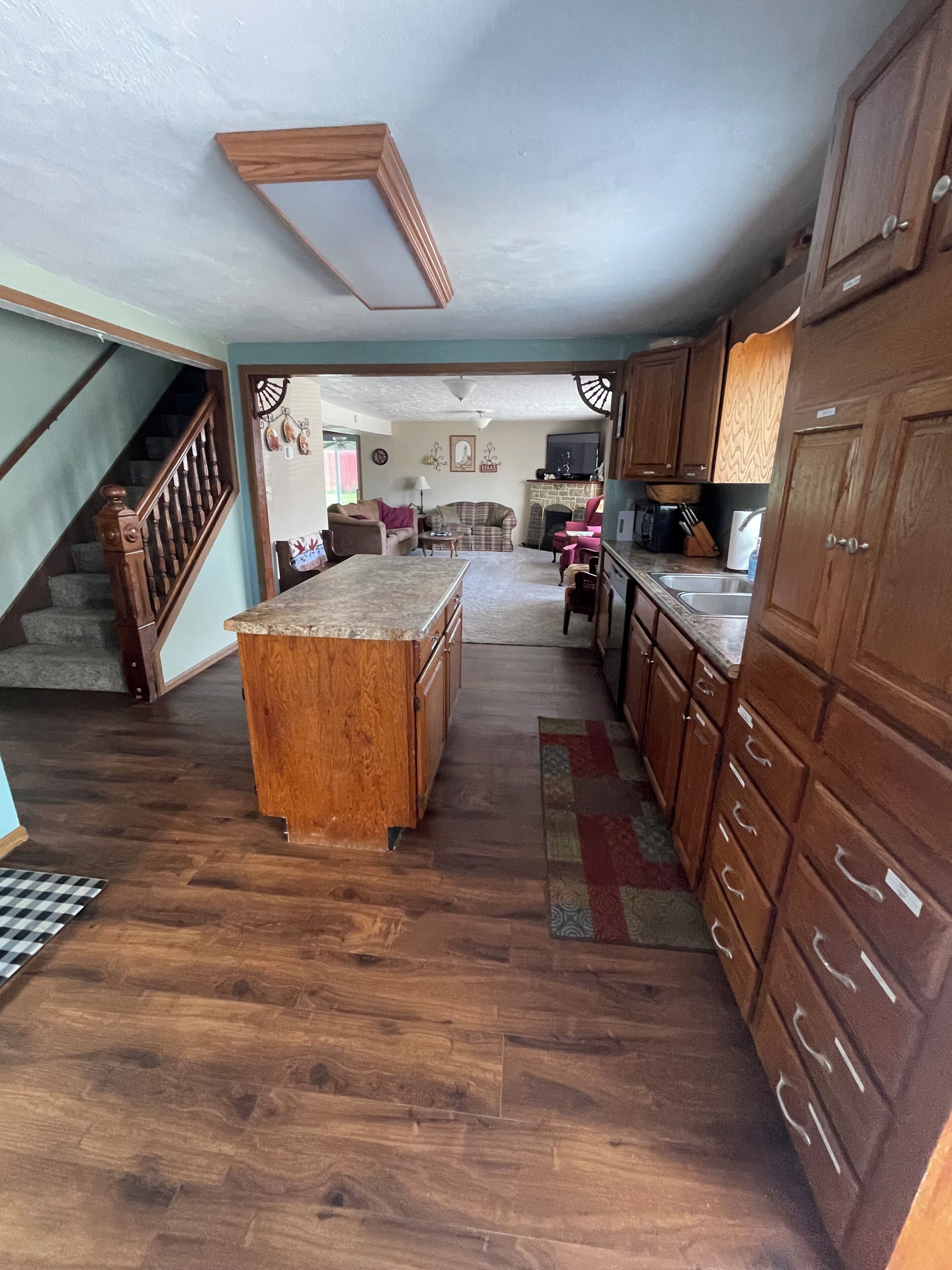 Une cuisine avec des meubles en bois, un îlot central et un escalier menant à un autre niveau.
