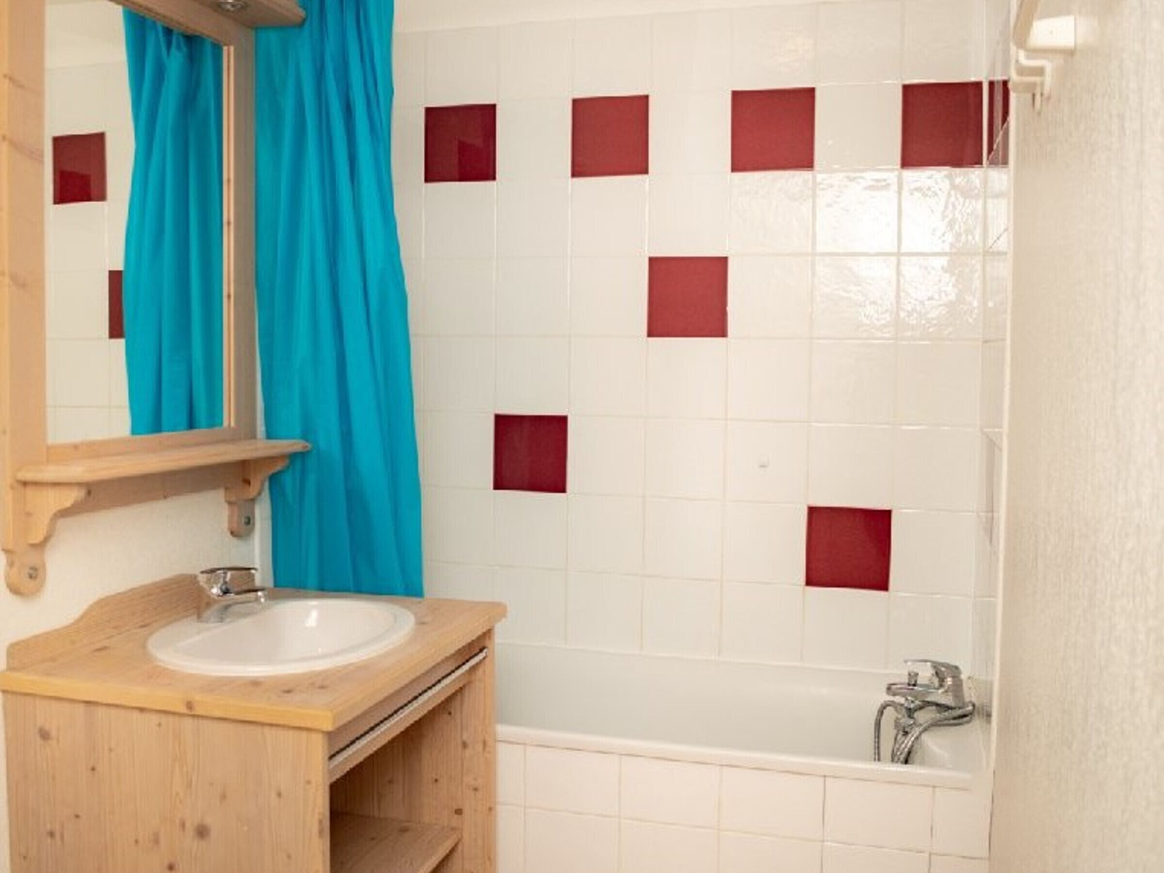 A bathroom with a wooden vanity, a mirror, a sink, and a bathtub.